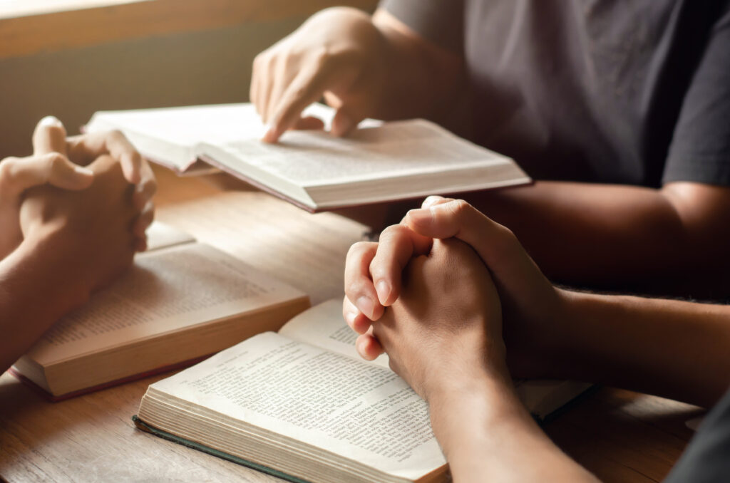 Believers gathered in prayer around an open Bible